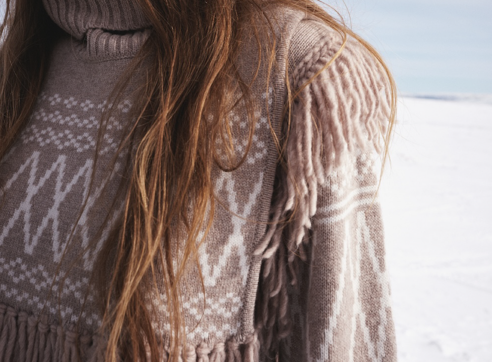 We Norwegians | FW25 | Woman wearing the Setesdal sweater along with the Setesdal bib in Sand against the backdrop of snowy Geilo