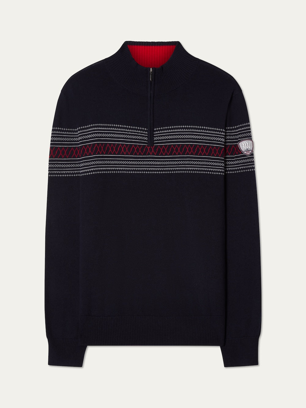 The We Norwegians Signature Zip Up Men is a navy Merino wool sweater with red and gray Norwegian Setesdal pattern on the chest and sleeves, a small embroidered patch on the left upper arm, and a red inner collar.