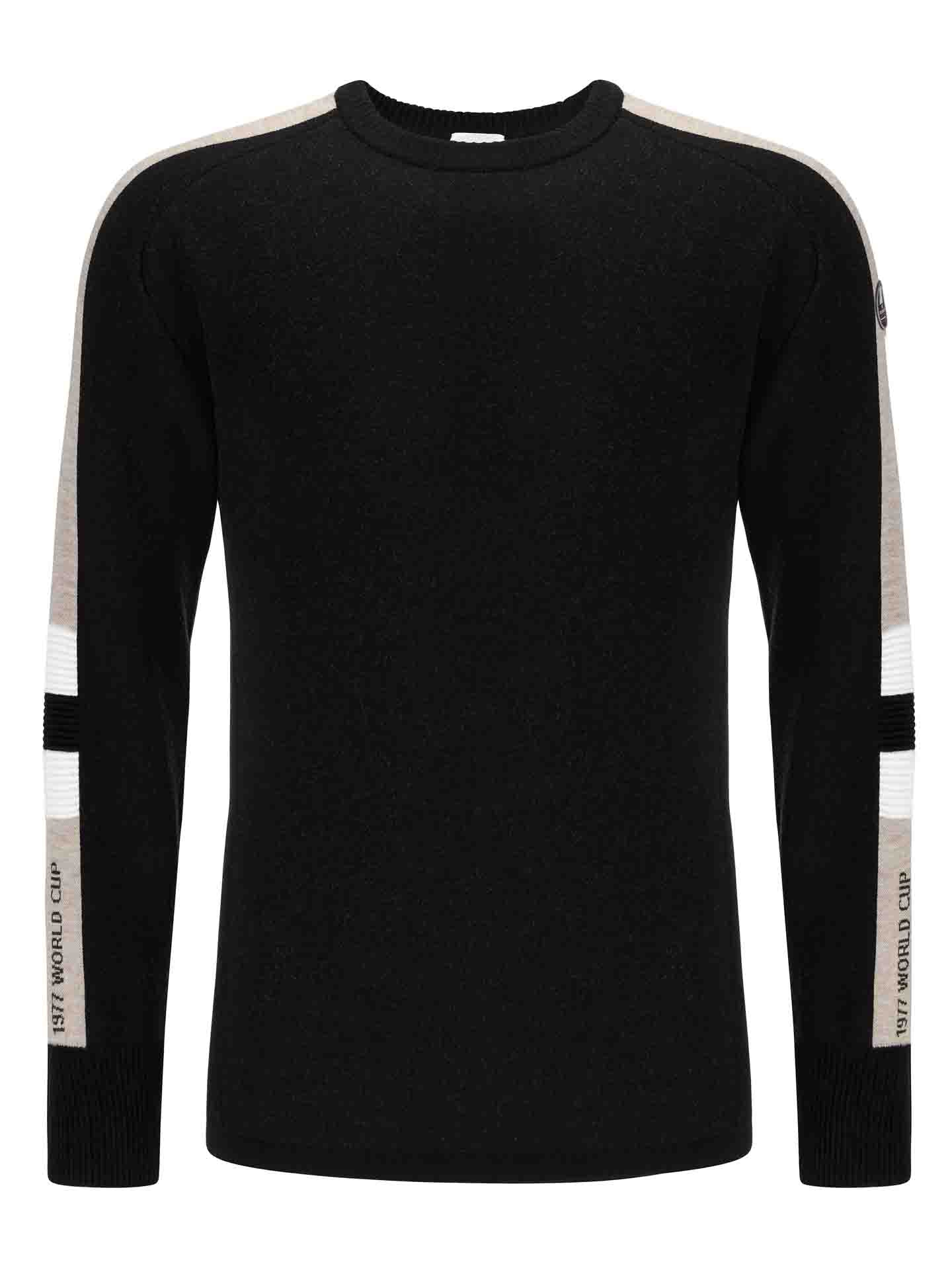 The Hafjell Crewneck Men Black by We Norwegians is a black long-sleeve ski sweater featuring beige and white striped accents along the shoulders and sleeves. It has "Kitz Wooley Club" printed in white on the arm bands. Made from fine merino wool, this sophisticated sweater boasts a round neckline and ribbed cuffs.
