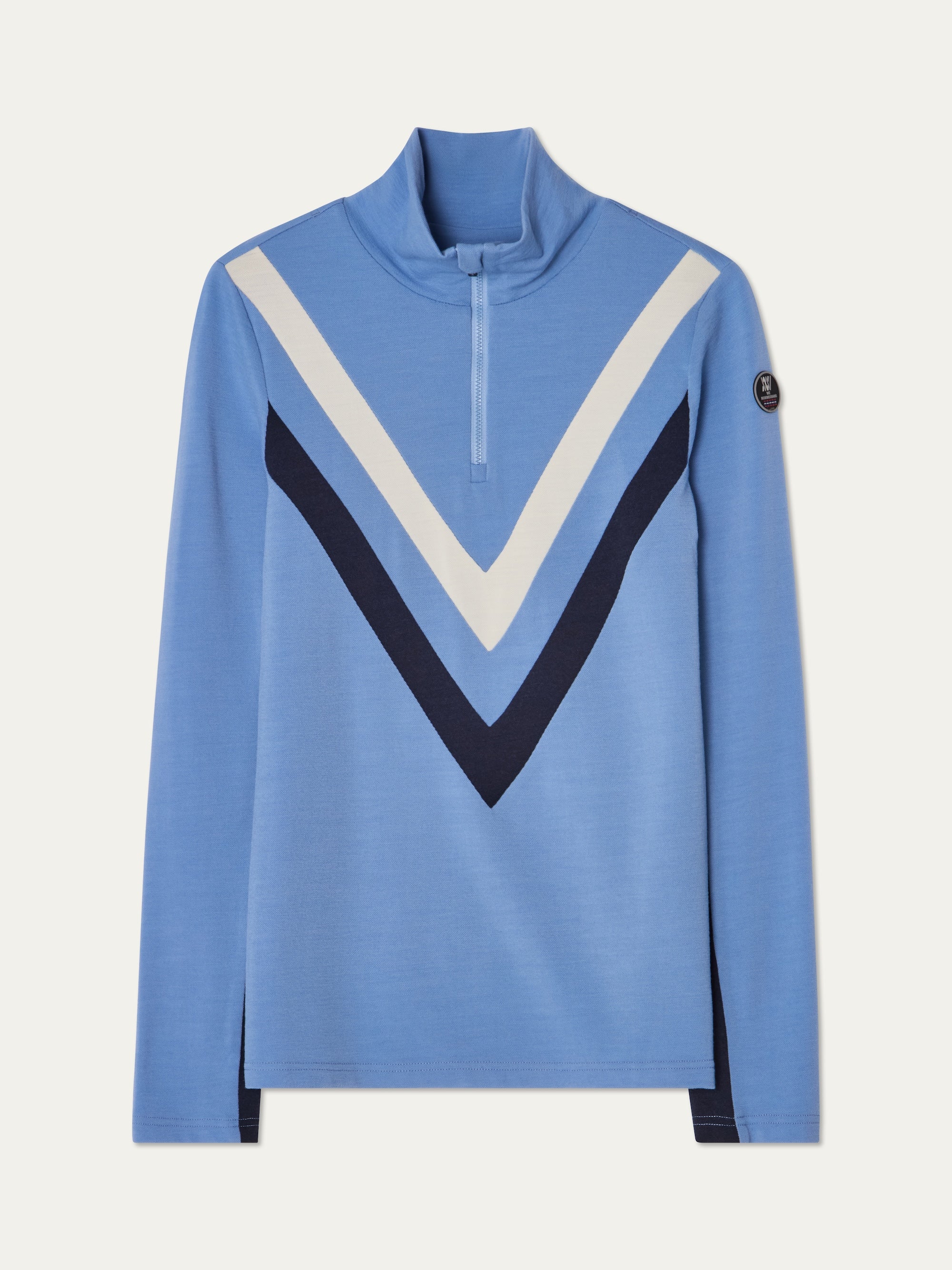 The We Norwegians Voss Chevron ZipUp Women is a light blue long-sleeve Merino wool pullover featuring a quarter-zip collar, bold white and navy V-shaped stripes on the front, and a small round patch on the left sleeve.