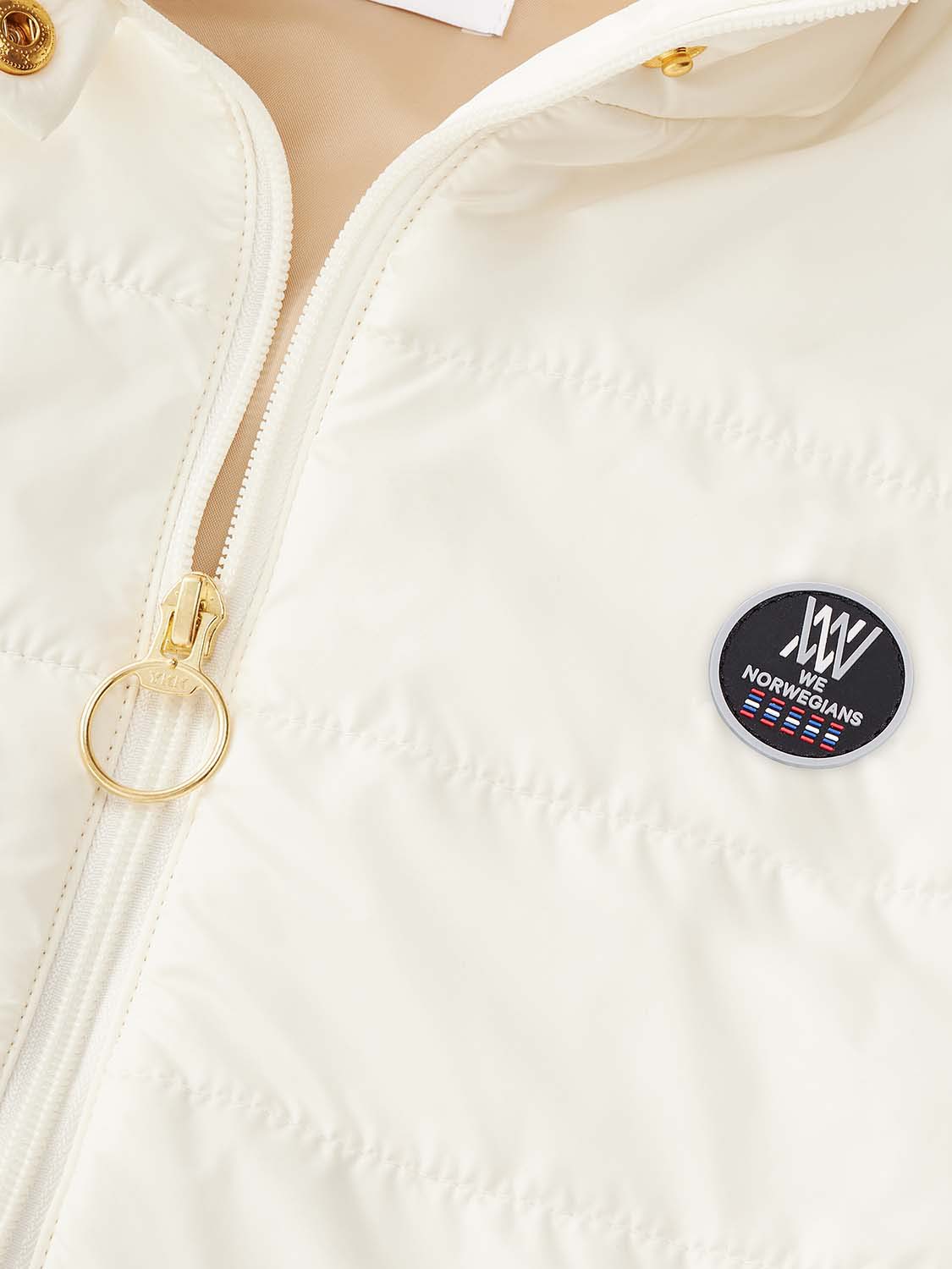 Close-up of the Myrken Lavalan Vest Women White by We Norwegians, crafted from water repellent fabric. It features a circular black emblem on the left chest with the text "We Norwegian," a small graphic of a flag, and a stylized "W" logo. The jacket includes a gold zipper pull tab shaped like a ring.