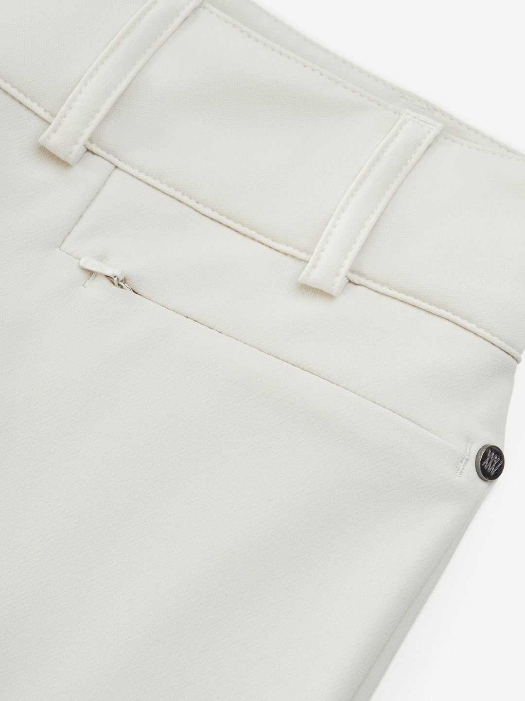 Close-up of the back of a pair of We Norwegians' Lista Pant Women in Cream. The image highlights a belt loop, a closed pocket with a barely visible white zipper, and a small black button or pin near the seam. The fabric appears to be smooth and well-stitched.