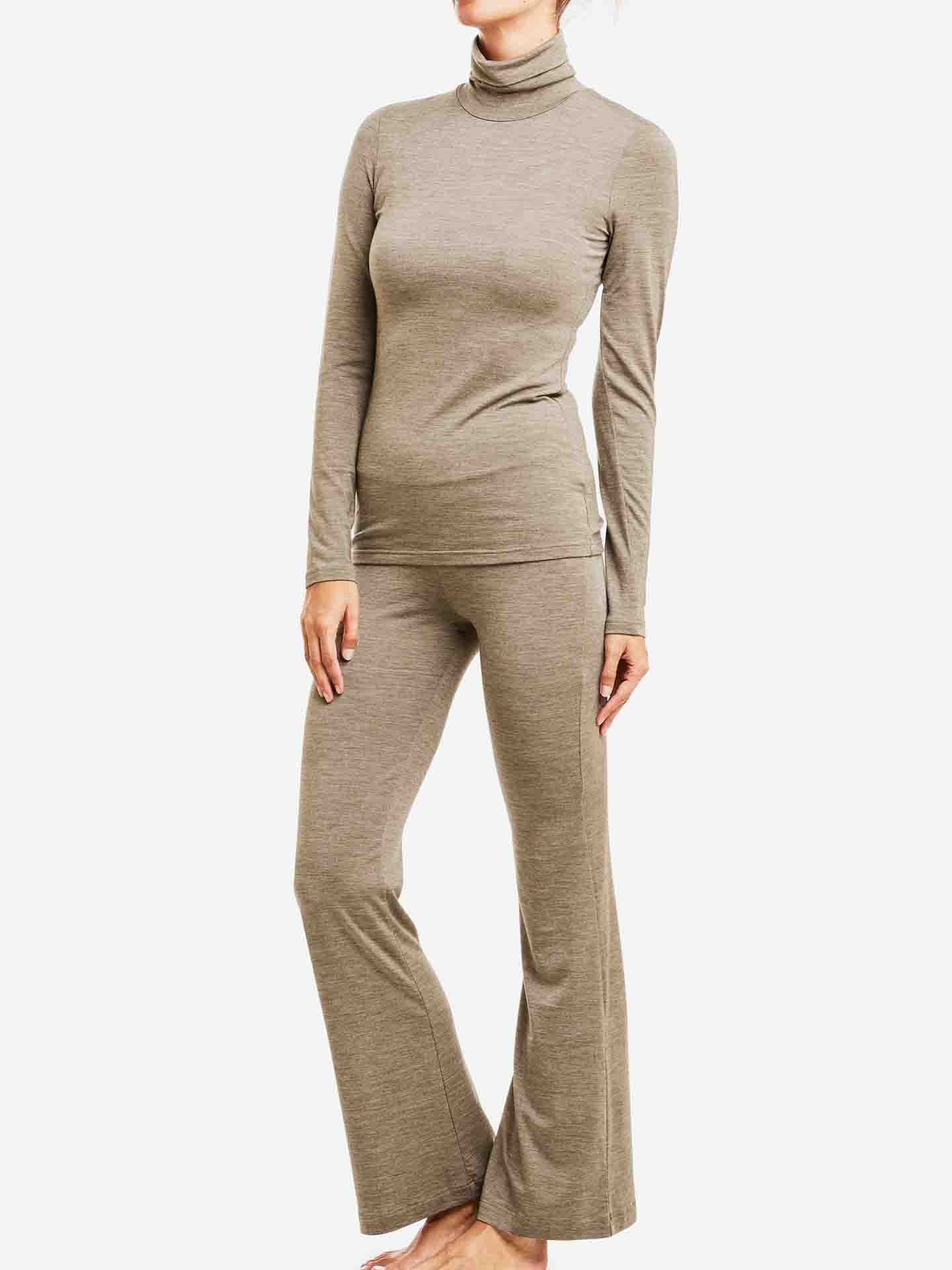 A person is standing barefoot, wearing a snug-fitting, long-sleeve Hygge Turtleneck by We Norwegians and matching flared pants in a light olive green color. The comfortable outfit made from Tencel exudes a casual vibe against the plain white background.