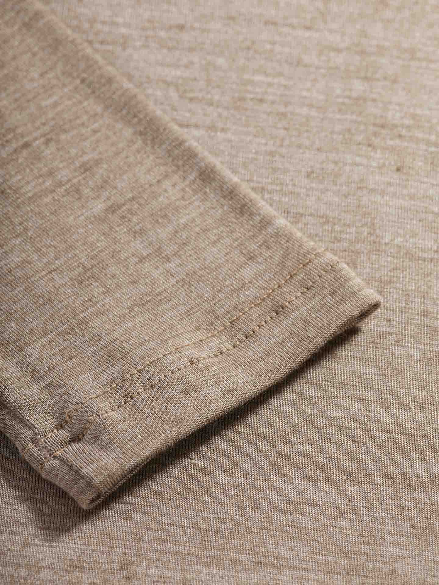 Close-up of the corner of a folded Hygge Turtleneck Women fabric by We Norwegians, showing its texture and stitching detail. The fabric appears to be lightweight and smooth, suitable for clothing or other textile applications. The stitching is neat and evenly spaced.