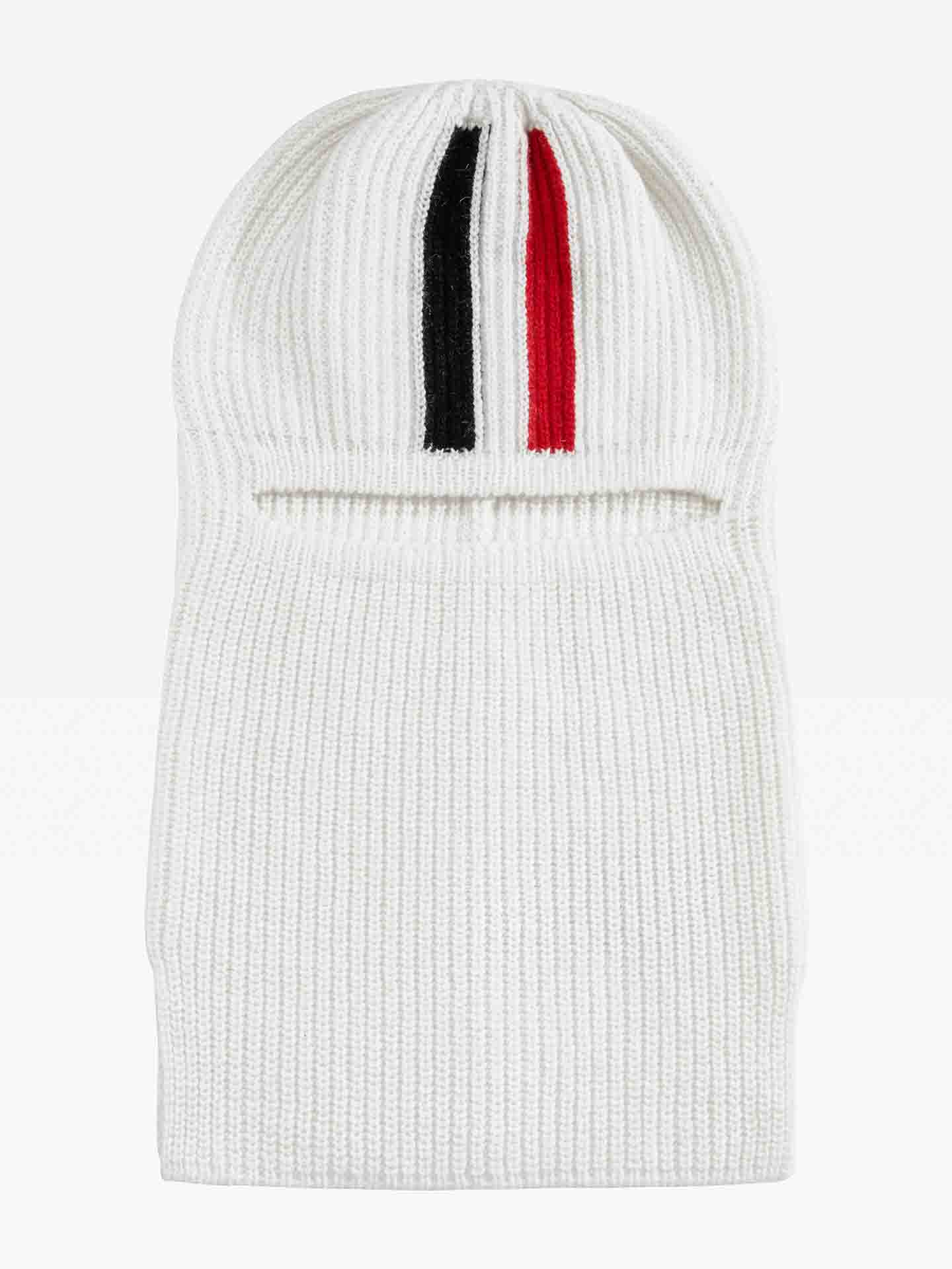The Apres Ski Balaclava from We Norwegians features a stylish white knitted design accented with vertical black and red stripes on top. Made from luxurious merino wool, this mask includes an opening for the eyes and provides complete coverage for the head and neck, capturing the essence of 70s ski fashion.
