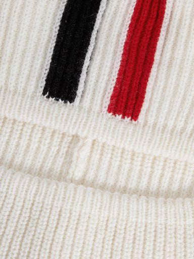 Close-up of the Apres Ski Balaclava from We Norwegians, showcasing its ribbed texture. The predominantly cream-colored merino wool knitwork features vertical stripes in black and red, reminiscent of 70s ski fashion, highlighting its intricate detail and texture.