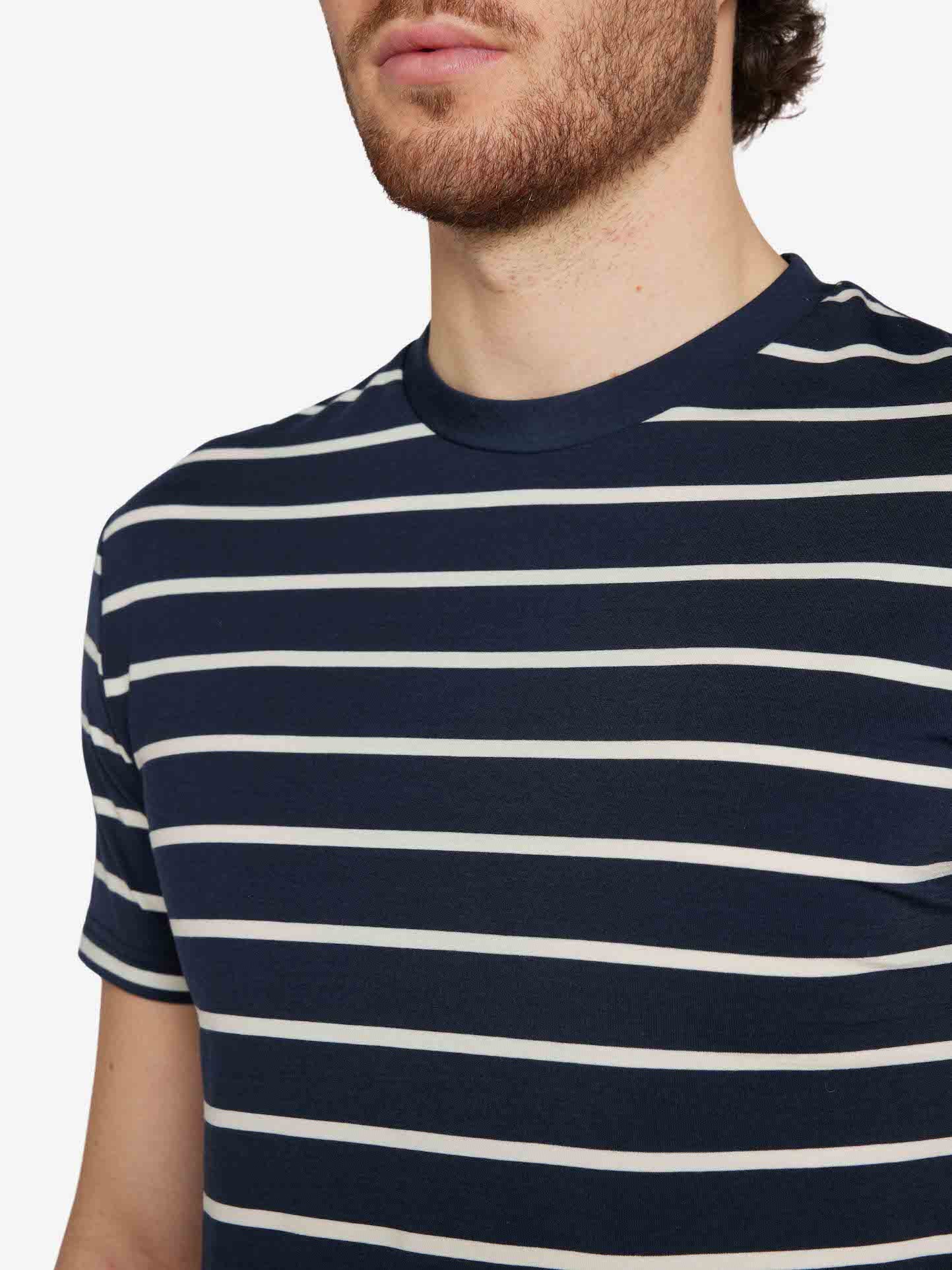 A person with a beard is wearing the Kragero Tee Men Navy, a horizontally striped navy blue and white t-shirt made of Merino Wool by We Norwegians. The image is cropped to focus on the upper torso and neckline, with the head partially out of frame against a plain white background.