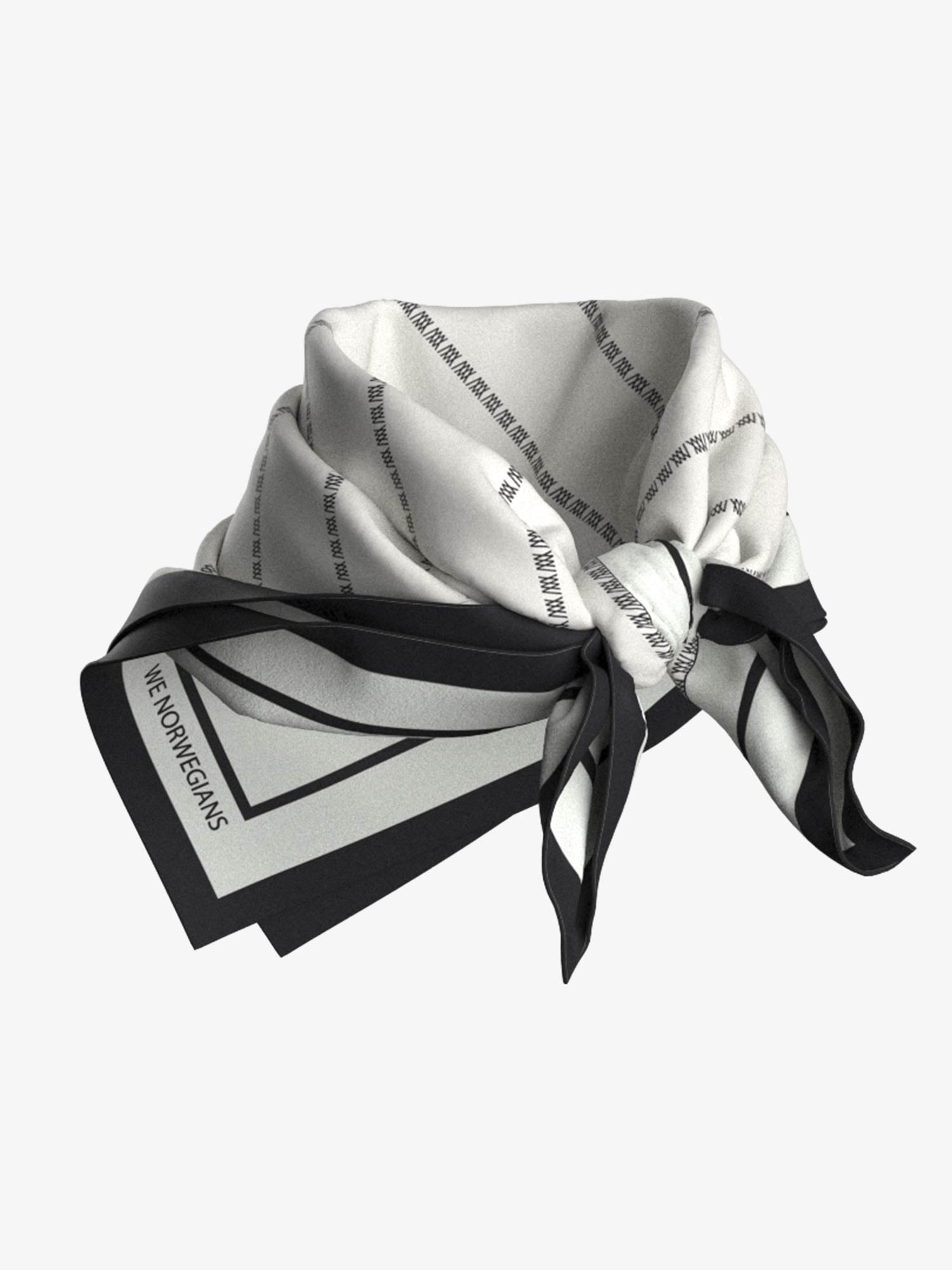 The Ship Silk Scarf White by We Norwegians is on display, showcasing a stylish designer look with a modern geometric pattern of alternating black, white, and gray sections. Folded and knotted elegantly, the silk-twill scarf features the "We Norwegians" text subtly printed along the edges.