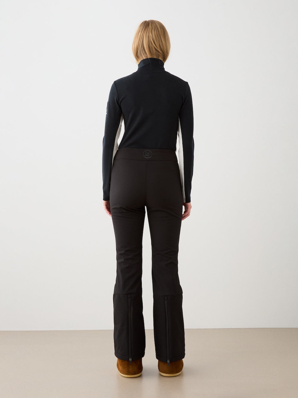We Norwegians | FW25 | Womens Voss 1/4-Zip_Black | Model is wearing this light knit top with a stand collar, 1/4th zipper opening and long sleeves - paired with black pants on an off-white background | Back