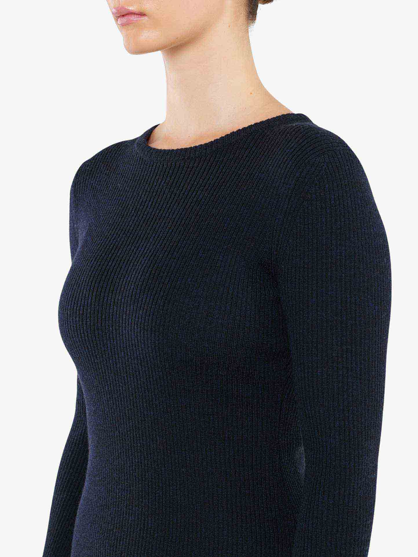 A person wearing the Geilo Ribbed Sweater Women by We Norwegians in black merino wool. The focus is on the upper torso, with the head partially visible, showing a clean neckline and minimal background.