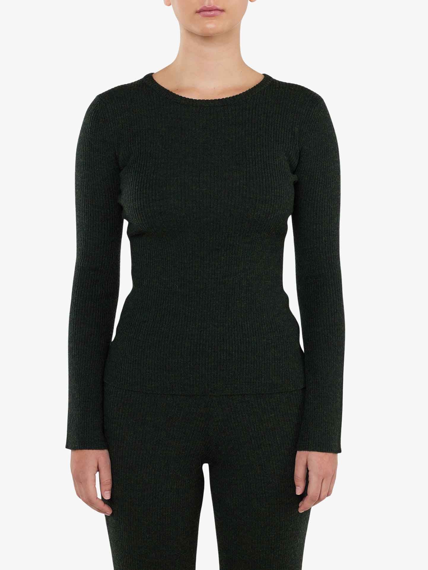 A person wearing the We Norwegians Geilo Ribbed Sweater Women, a fitted long-sleeve top in dark green, stands against a plain white background. Only the upper part of their body is visible, with their arms at their sides and their face partially out of the frame.