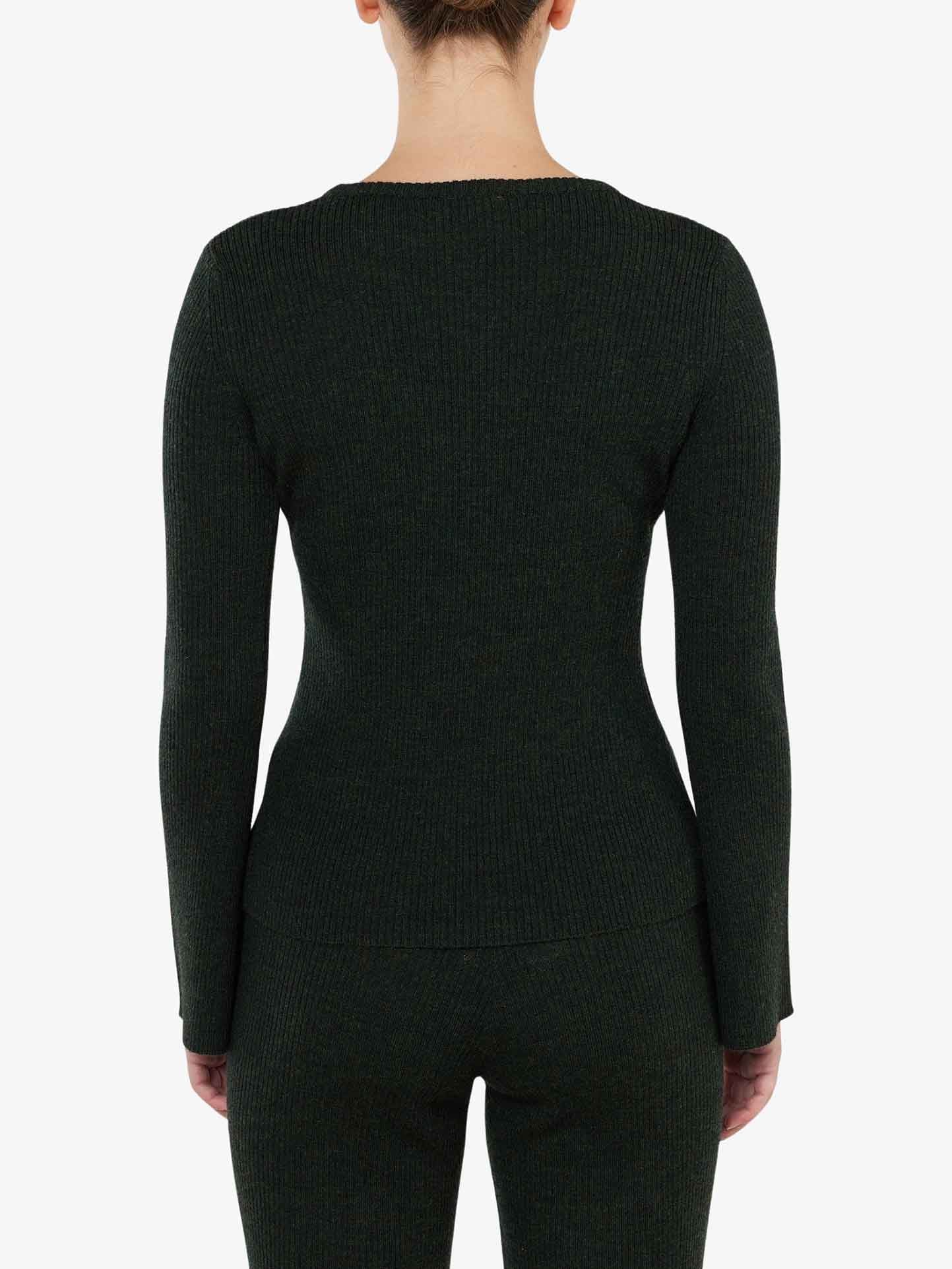 A person stands facing away from the camera, wearing the Geilo Ribbed Sweater Women by We Norwegians paired with matching pants. The dark green, long-sleeve top, crafted from cozy merino wool, perfectly contrasts with the plain white background, accentuating every detail of the outfit.
