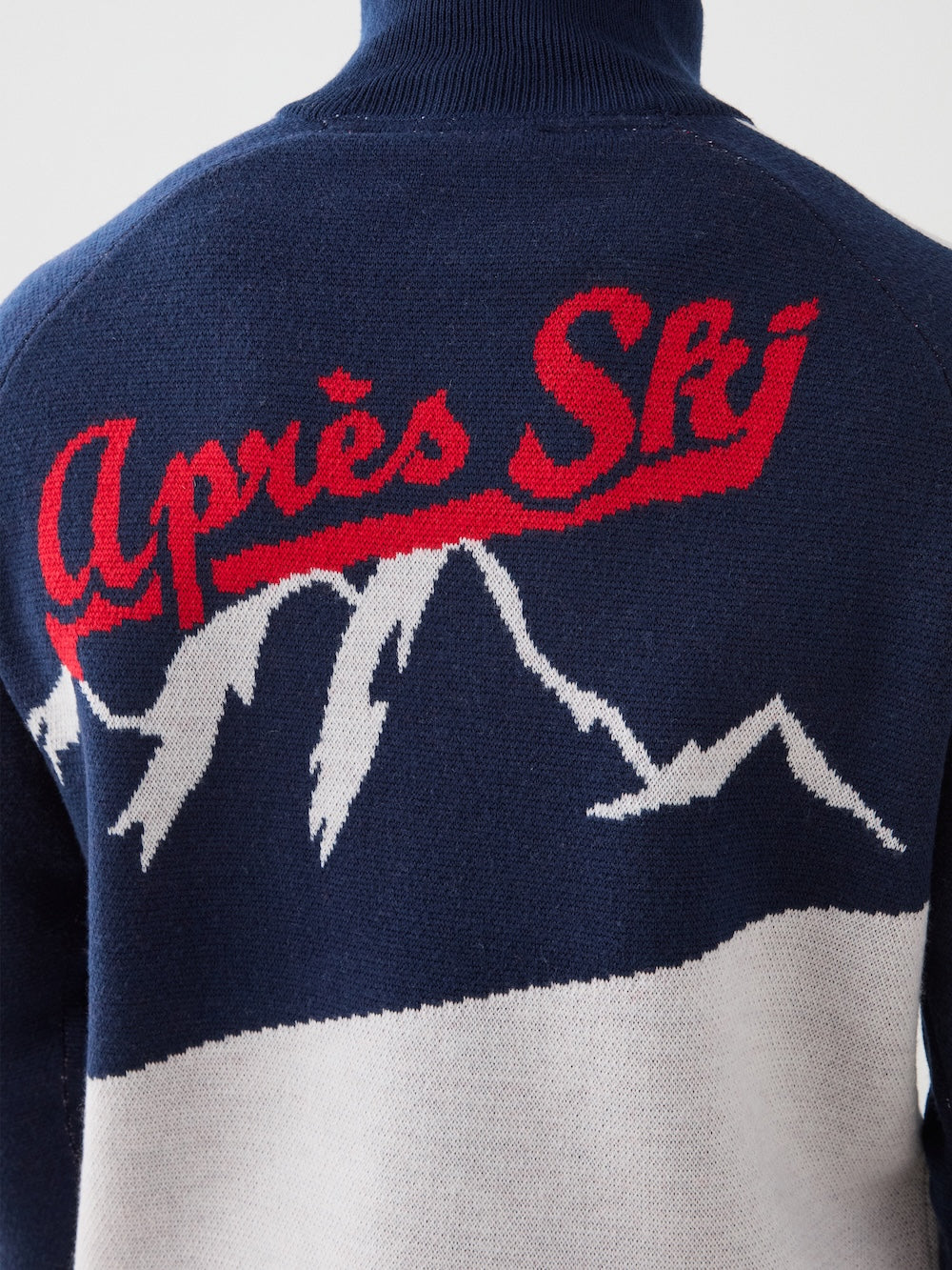 A close-up of the We Norwegians Afterski Sweater Men in navy, showcasing white mountain graphics and “Après Ski” in red cursive across the shoulders.