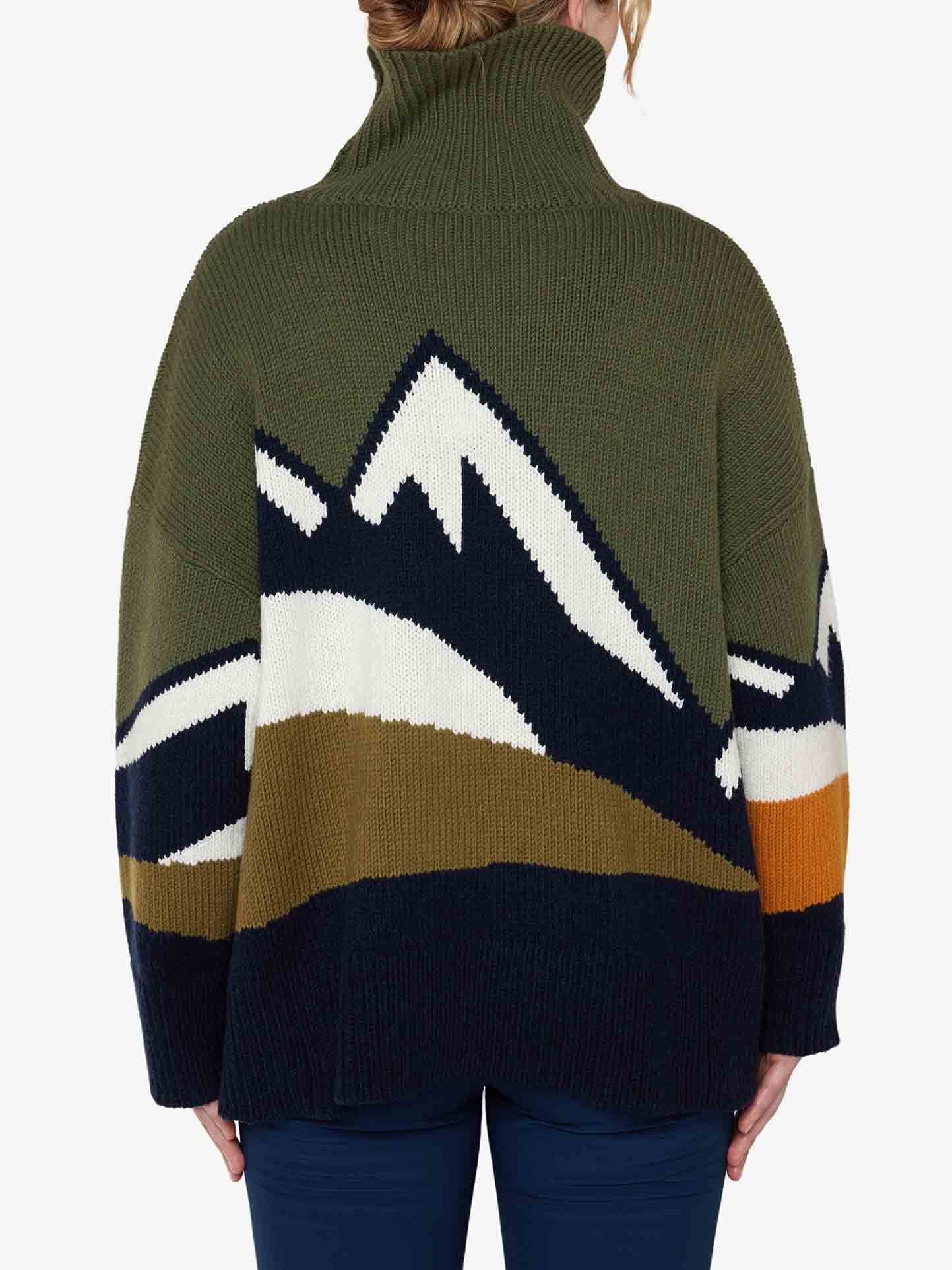 A person with light brown hair is wearing the cozy Snowmountain Sweater Women by We Norwegians, a dark green turtleneck featuring a mountain scene design on the back in white, black, olive, and orange. Perfect for fall fashion, the merino wool sweater keeps them warm as they stand with their back to the camera.