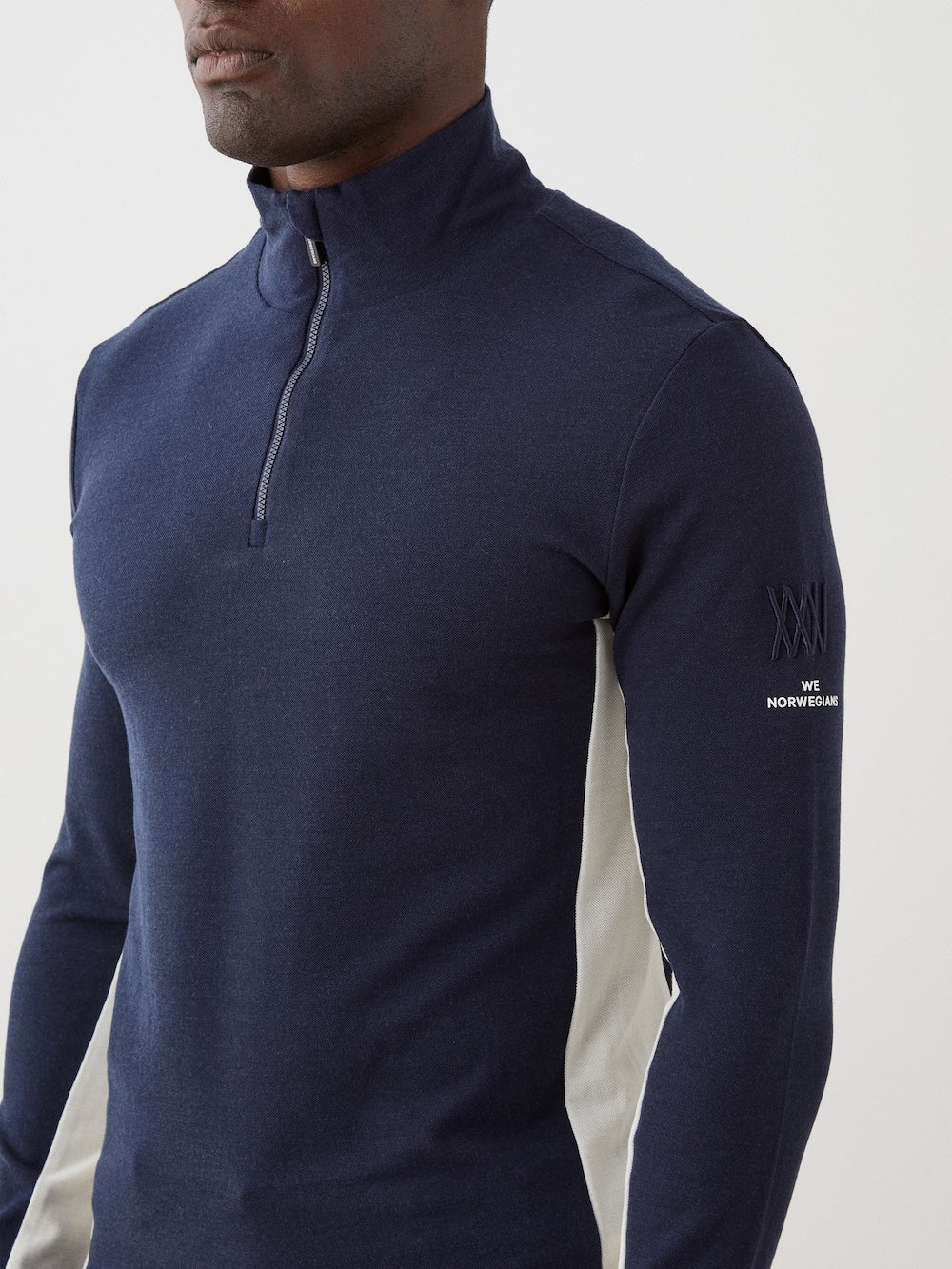 We Norwegians | FW25 | Mens Voss 1/4-Zip_Navy blue | Model is wearing this light weight knitted top with a stand collare, 1/4th zipper opening and long sleeves on an off-white background | Close-up