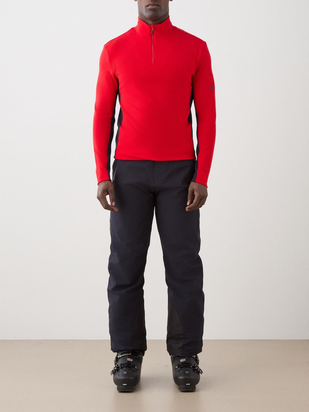 We Norwegians | FW25 | Mens Voss 1/4-Zip_Red | Model is wearing this light weight knitted top with a stand collare, 1/4th zipper opening and long sleeves - paired with black pants on an off-white background | Front