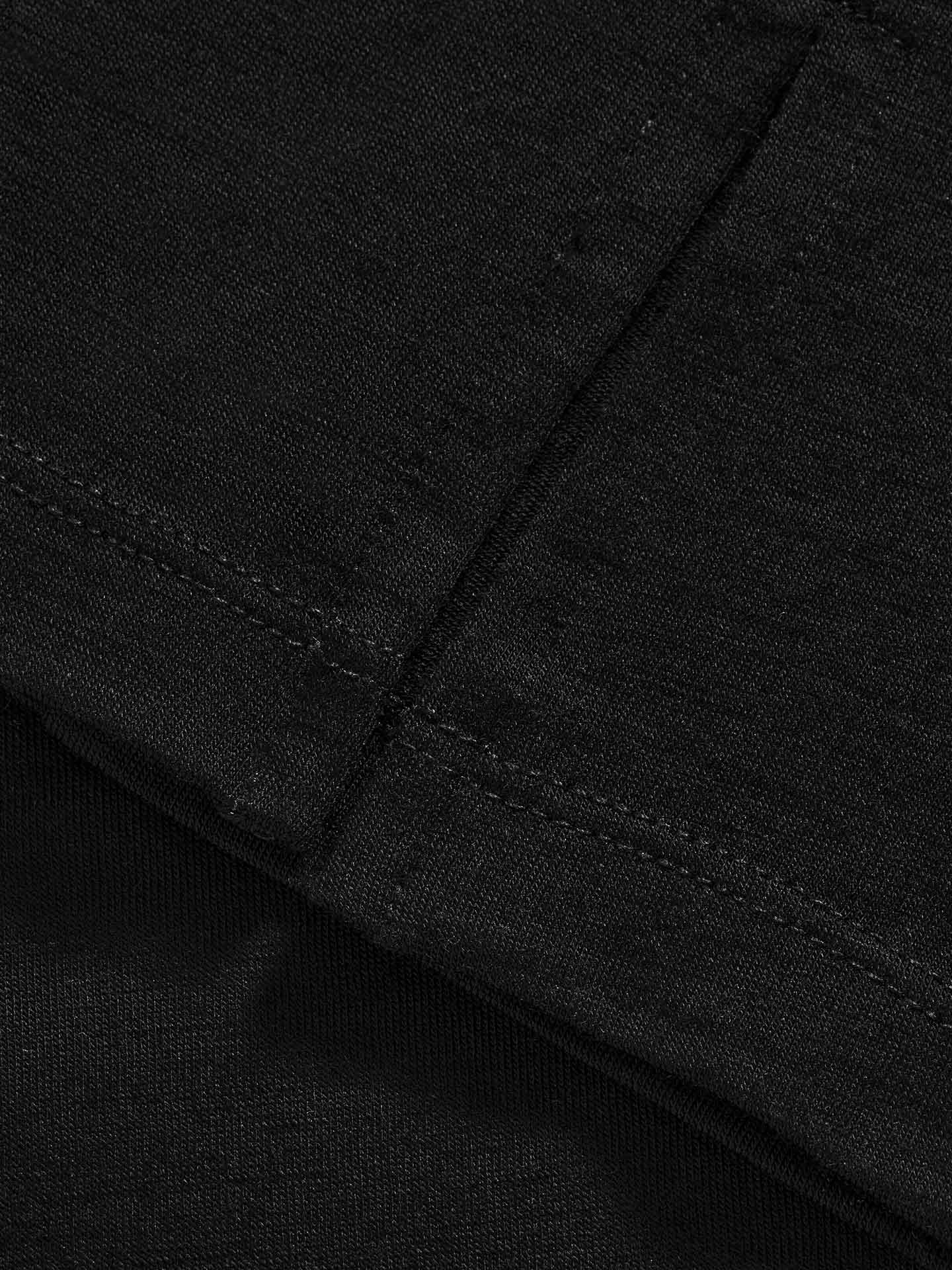 Close-up view of the Natt PJs Pants Women Black by We Norwegians, showcasing the black fabric with visible stitching and a textured surface that exemplifies their craftsmanship. The photo highlights two layers of material, showing where one layer is folded over and stitched to the other.
