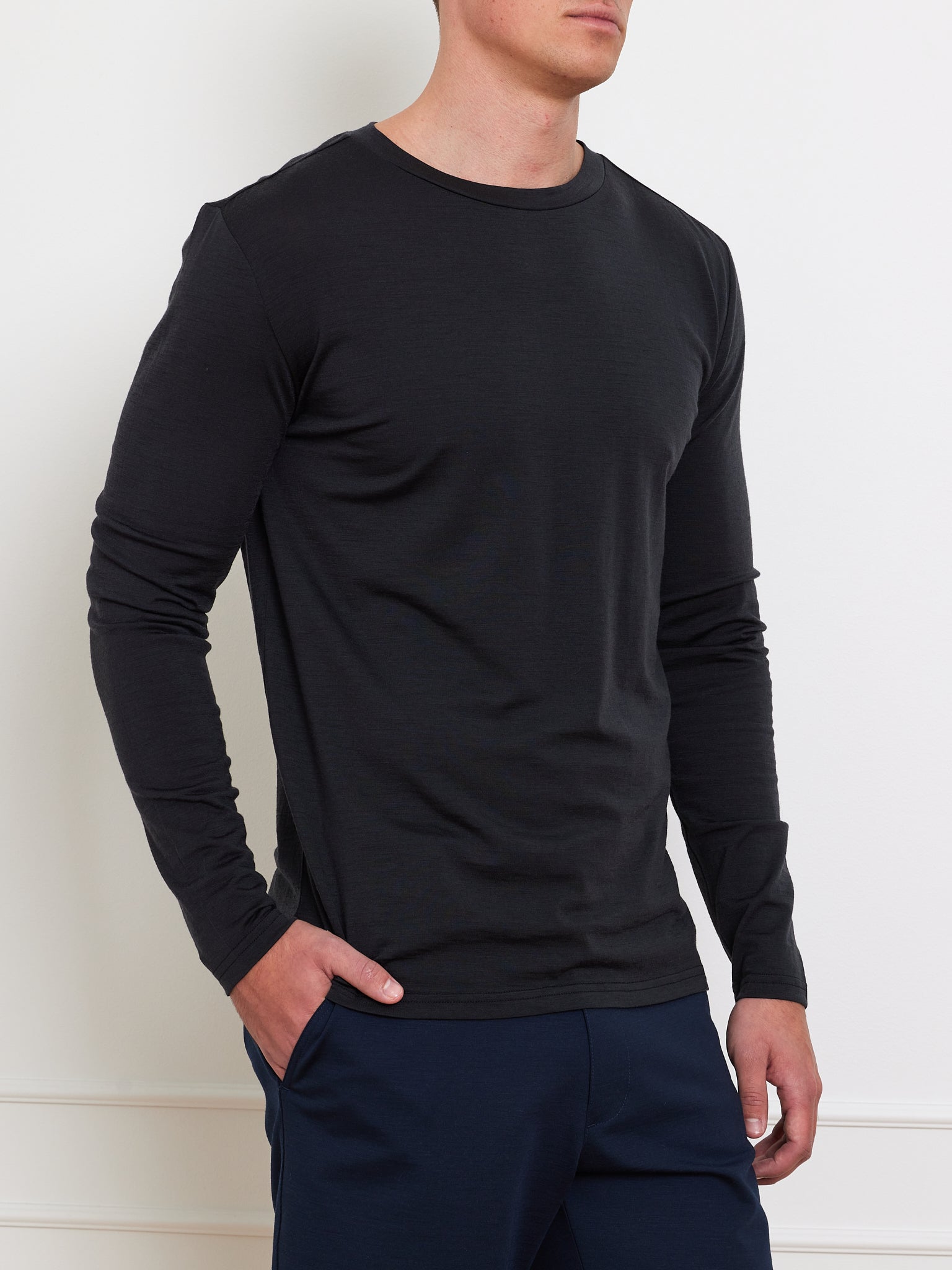 A person wearing the Berg LongSleeve Men shirt by We Norwegians stands with one hand in their pocket and dark pants against a light background.