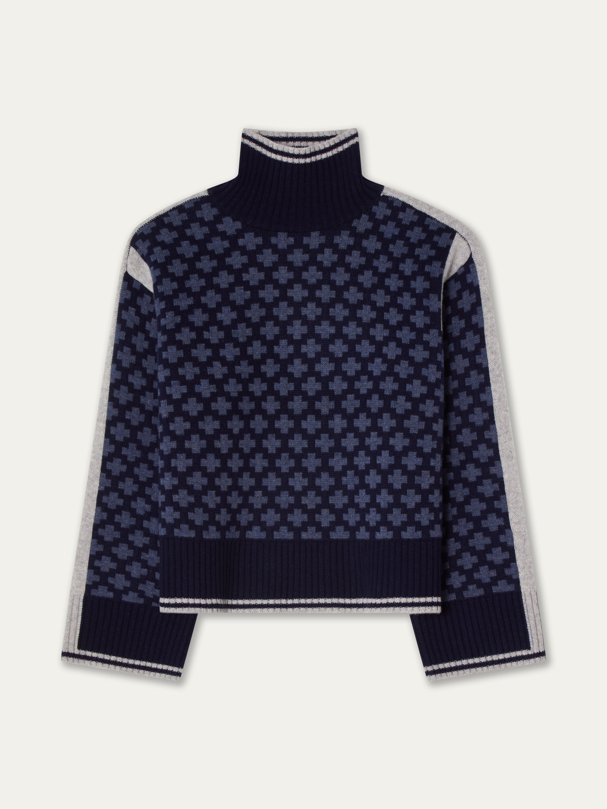 The We Norwegians Boat Sweater Women is a navy blue oversized knit with a geometric plus-sign pattern, light gray sleeve panels, and ribbed cuffs, collar, and hem.