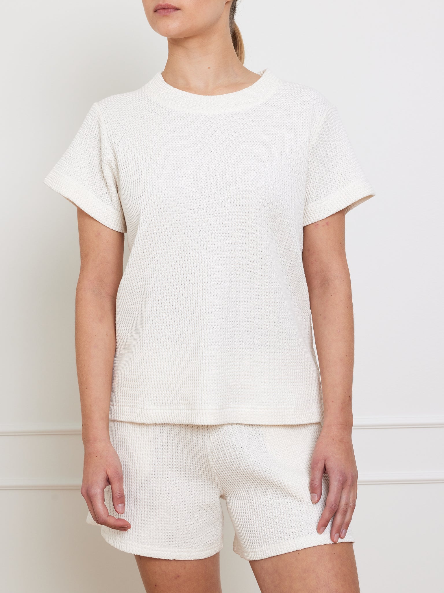 A person models the We Norwegians Waffle Tee Women, featuring a beige waffle-knit T-shirt and matching shorts, against a plain white backdrop. This outfit is a simple, casual wardrobe essential.
