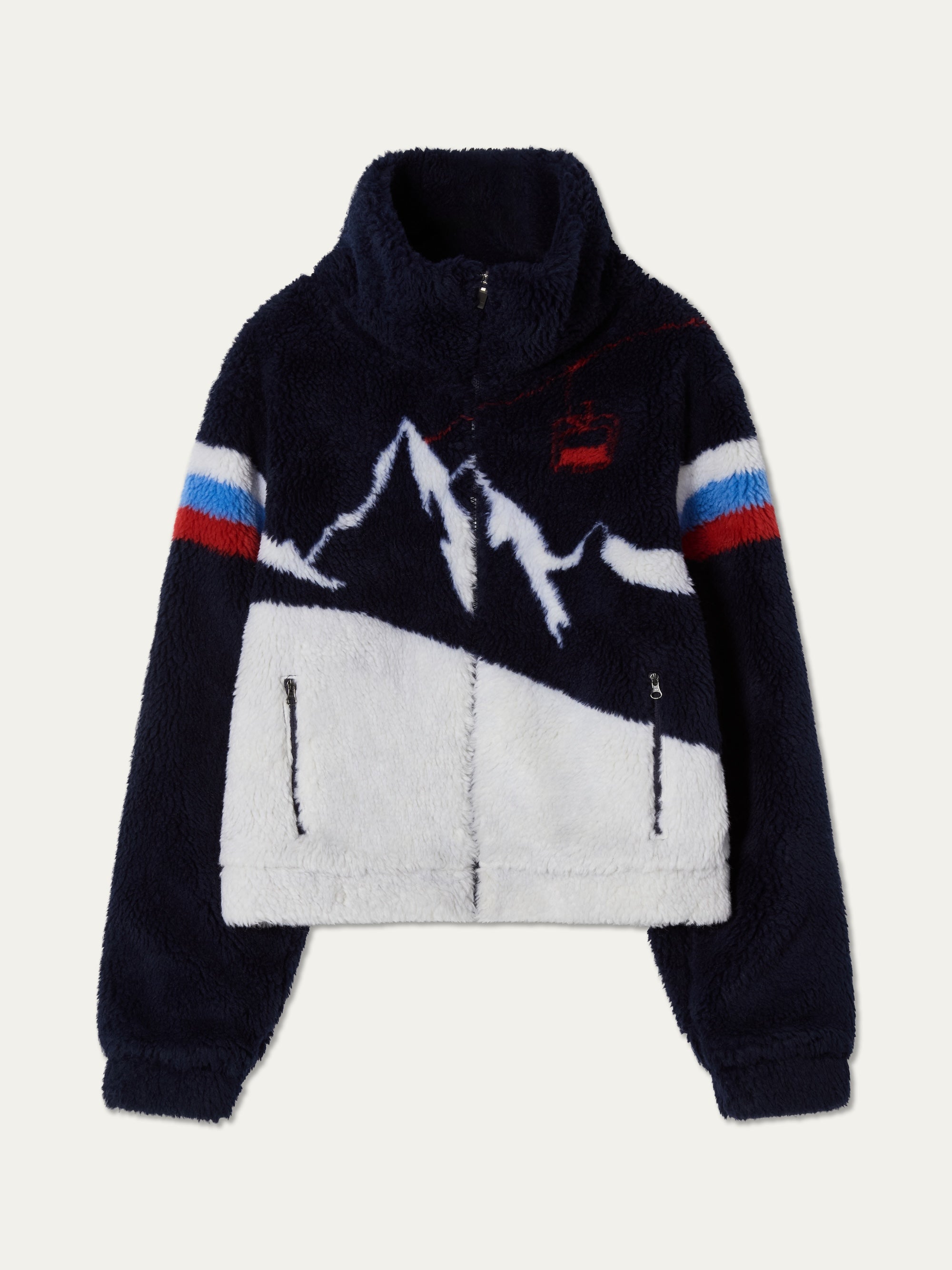The We Norwegians Snowmass Jacket for women is a navy and white jacquard fleece with a zip-up front, mountain graphic, red and blue striped sleeves, high collar, and two zippered pockets—an après-ski essential.