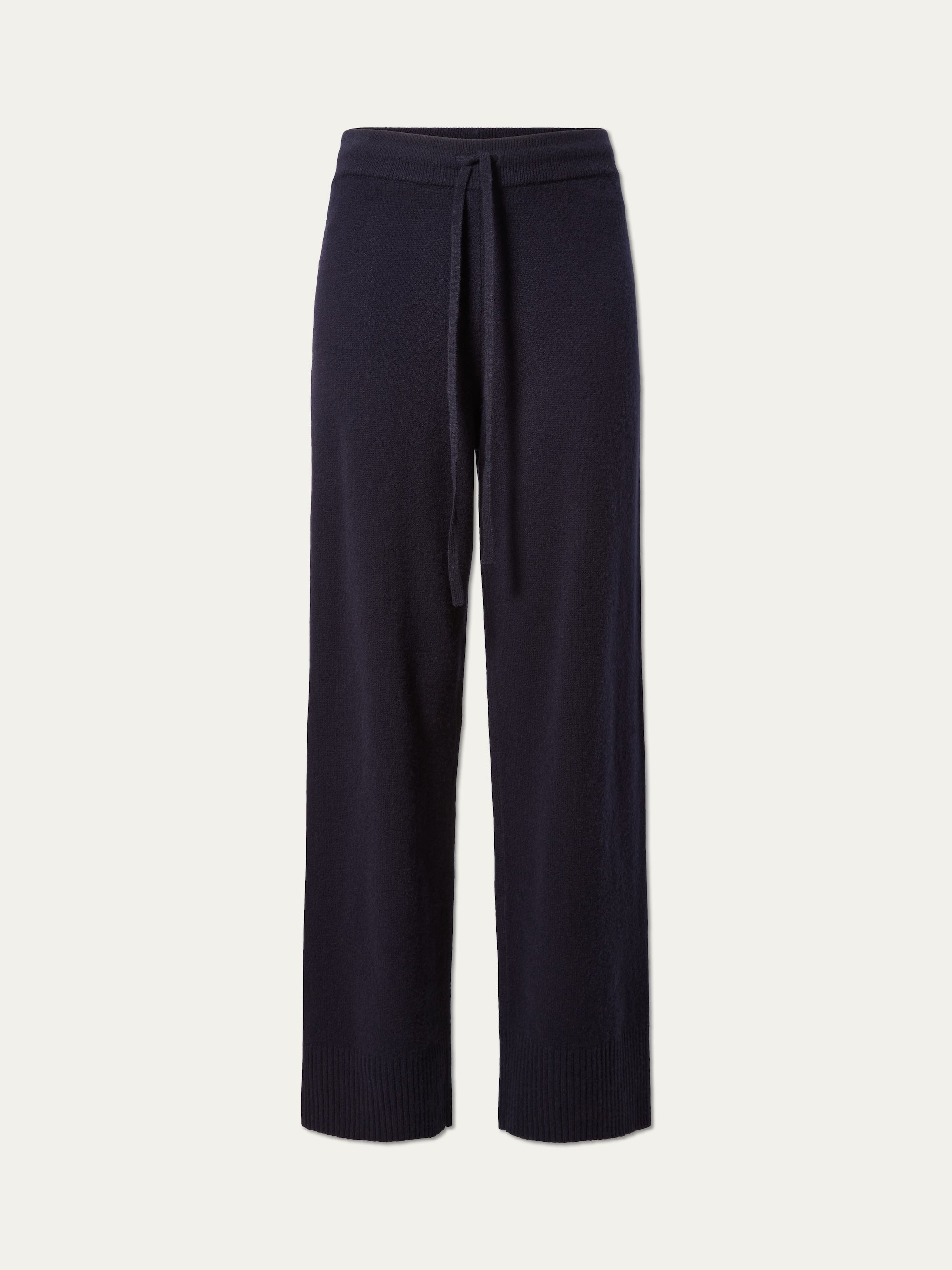 The Geilo Jogger Women by We Norwegians are black knit pants featuring a wide-leg silhouette, elastic waistband, and drawstring tie, shown against a plain white background.