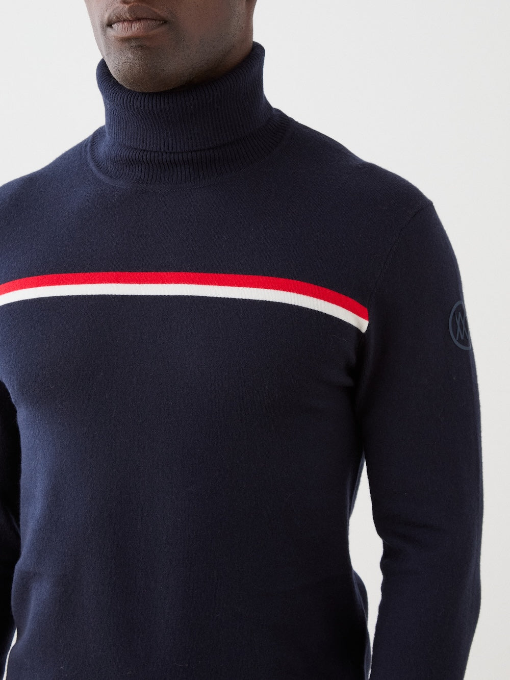 Navy turtleneck sweater with red and white stripe on a plain background