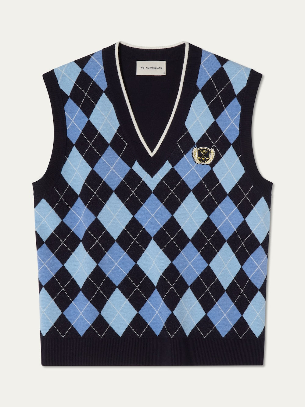 The We Norwegians Fairway Vest Women is a sleeveless golf vest with a blue, black, and white argyle knit pattern, V-neckline, and a small embroidered crest patch on the chest.