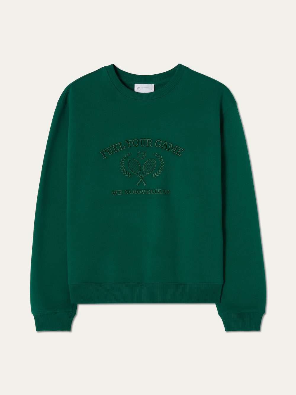 The We Norwegians Bounce Sweater Women is a green crew neck with ribbed cuffs and hem, featuring subtle tennis embroidery on the front—"FUEL YOUR GAME," "WE NORWEGIANS," and two rackets with a ball for an athletic, stylish touch.