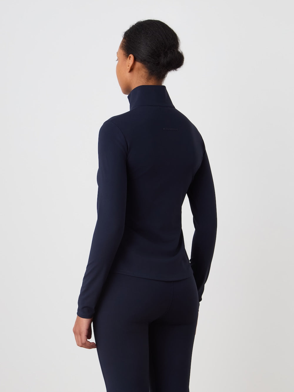 Person wearing a navy turtleneck and leggings set on an off white background