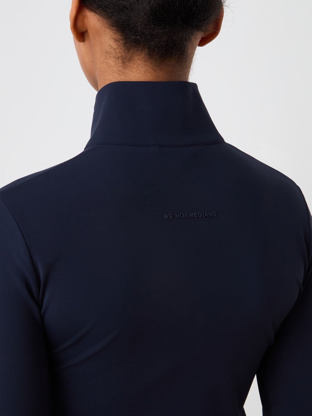 Navy blue turtleneck with a brand logo on the back against a light gray background