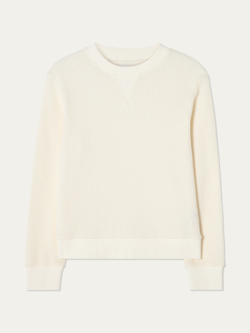 The We Norwegians Waffle Crewneck Women is a relaxed-fit, off-white cotton sweater shown against a neutral background. It features long sleeves, ribbed cuffs, hem and collar, plus a subtle V-stitch beneath the neckline.