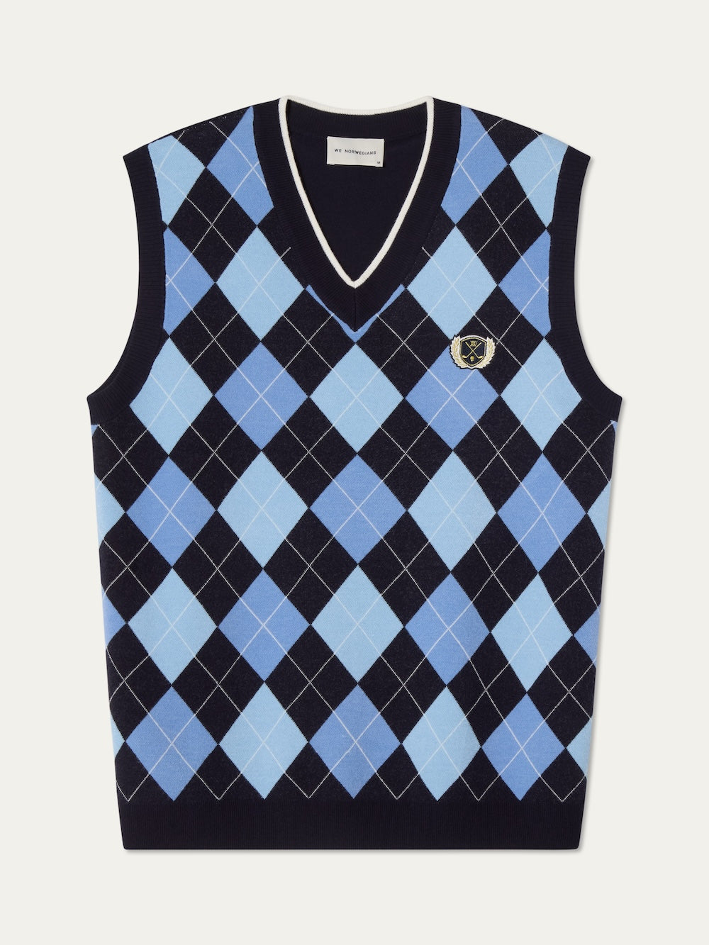The Fairway Vest Men by We Norwegians is a sleeveless sweater vest featuring a blue, black, and white argyle knit pattern with a small crest on the left chest and black trim—perfect for classic golf style.