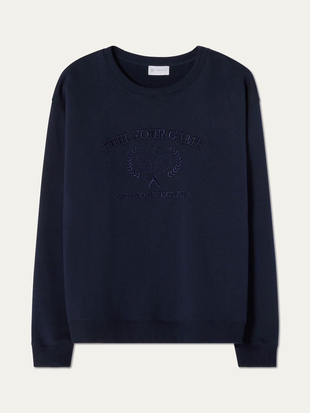 The We Norwegians Bounce Sweater Men is a navy blue velour crewneck with ribbed cuffs and hem, featuring crossed tennis rackets, laurel branches, and "FUEL YOUR GAME" embroidery for a vintage tennis-inspired look.