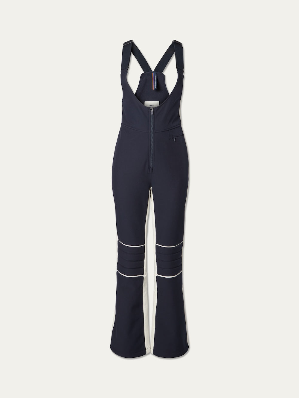 The Solo Bib Pant Women by We Norwegians features navy blue fabric with white piping, a front zipper, flared legs, adjustable straps, and a fitted waist for vintage-inspired alpine style on or off the slopes.
