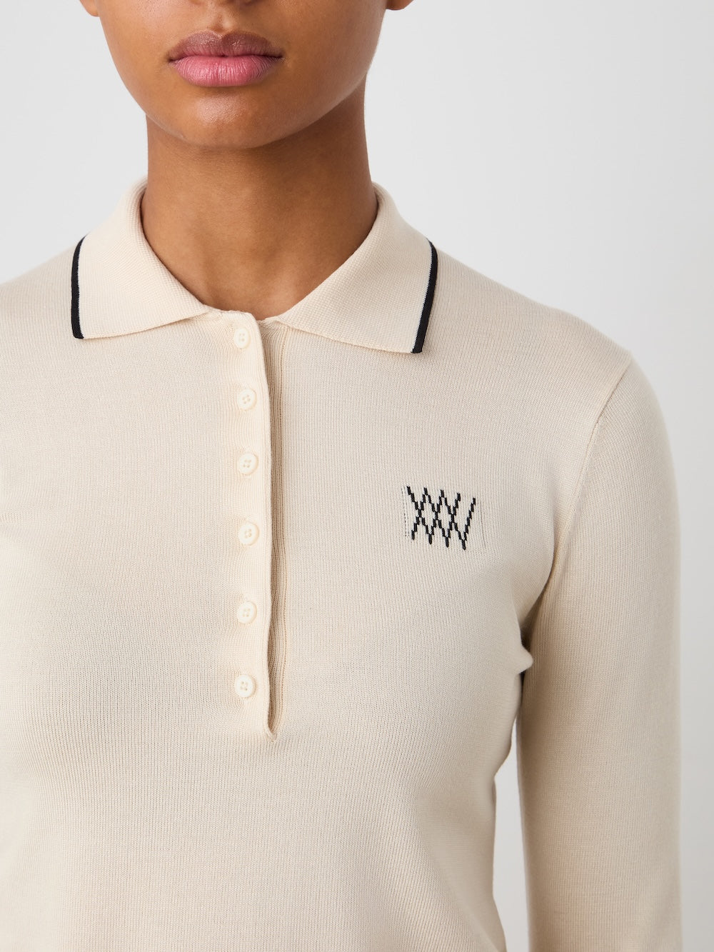 Beige polo shirt with a logo on the chest against a neutral background