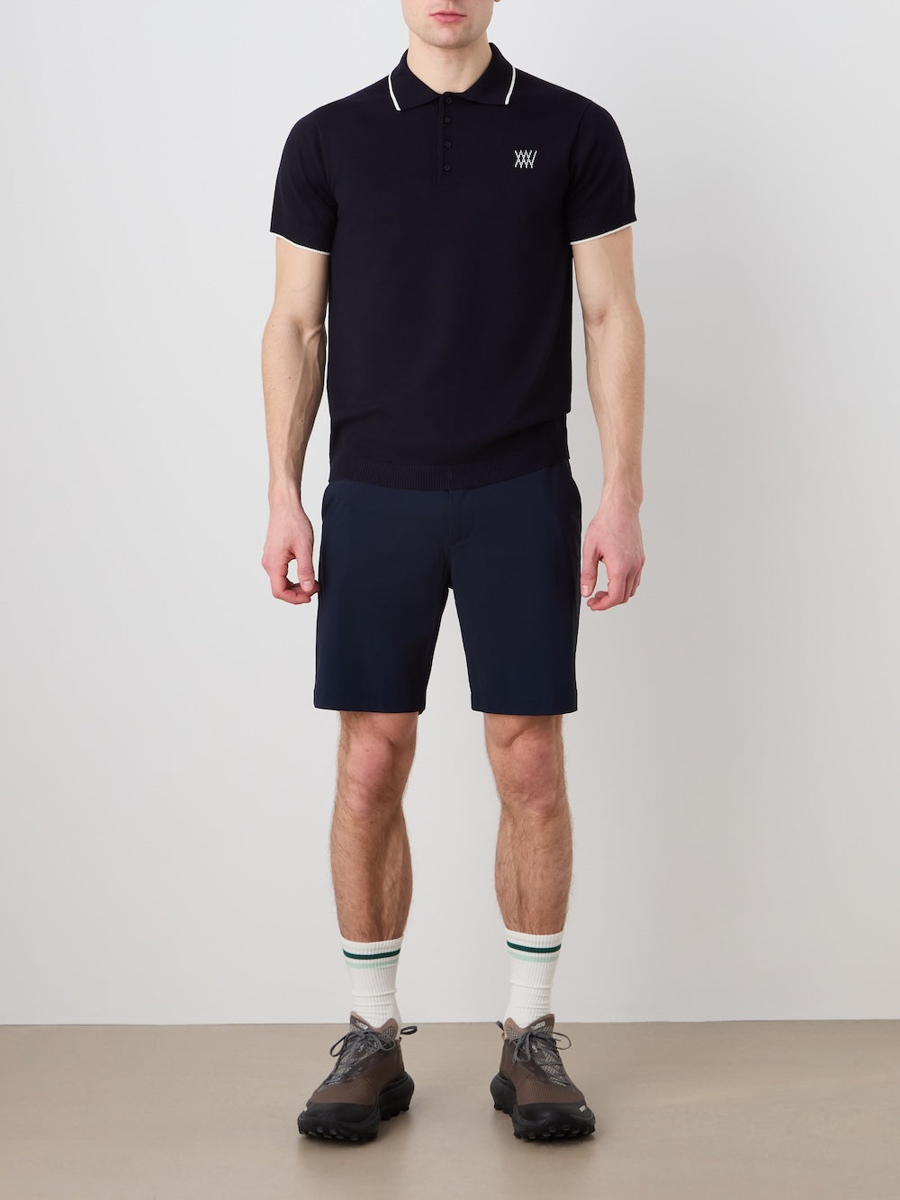 Person wearing a navy blue polo shirt, navy blue shorts against a plain background