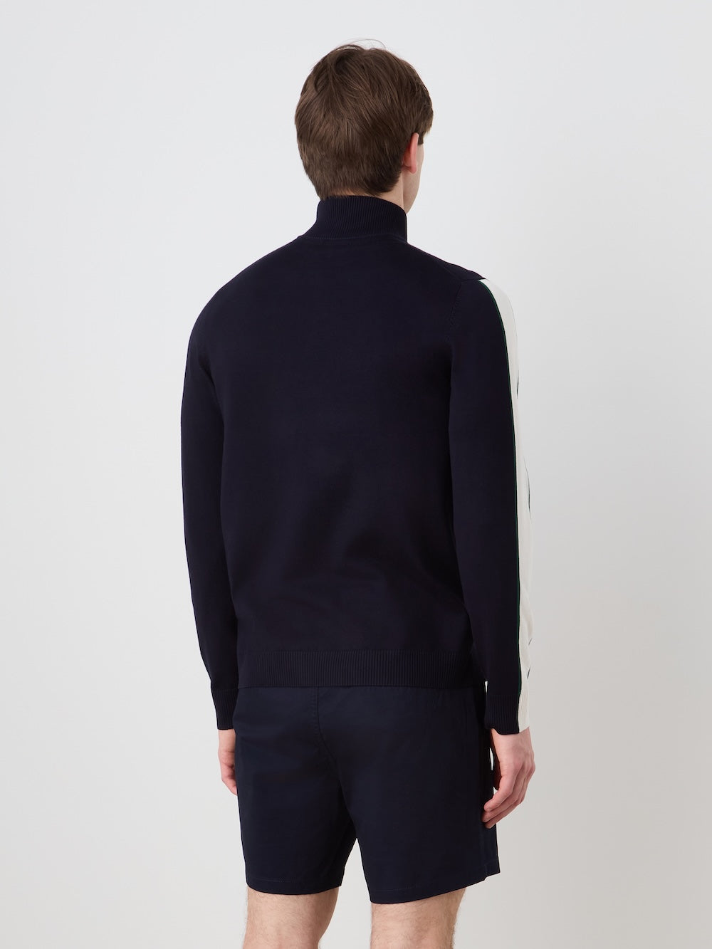 A person with short brown hair, seen from behind, wears the We Norwegians Grand Slam Sweater Men in navy with light sleeve stripes and matching navy shorts, standing against a plain white background.