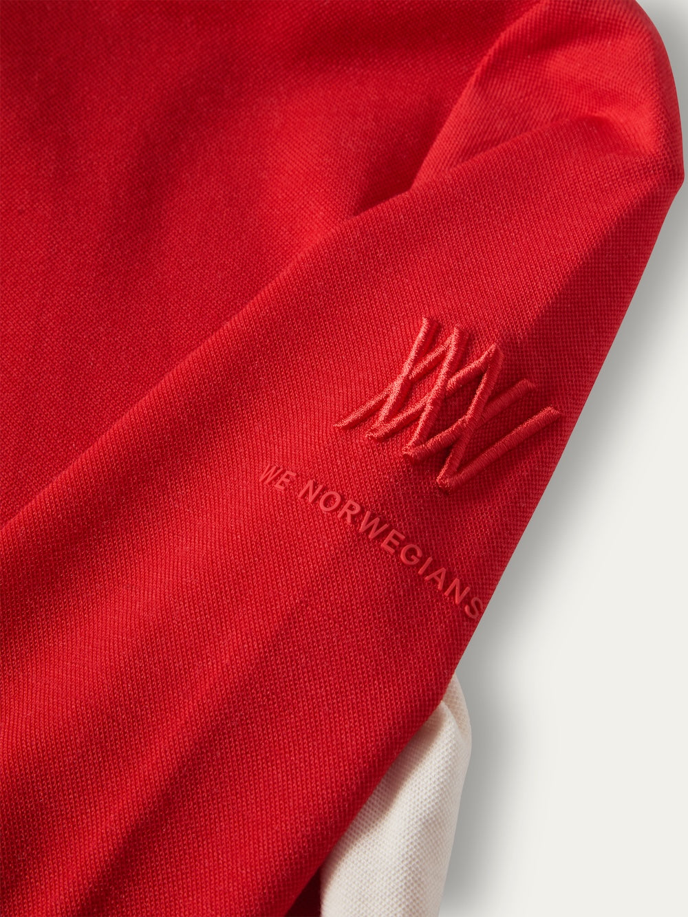 Close-up of a red Voss ZipUp Women sleeve featuring an embroidered logo and the text “WE NORWEGIANS.”
