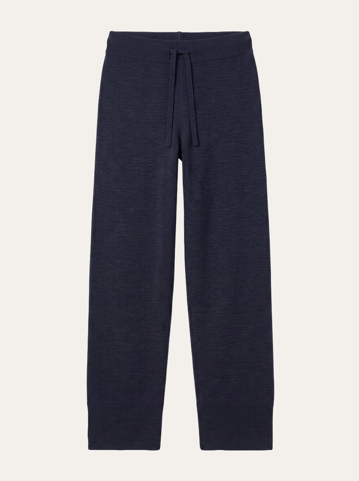 The Geilo Track Pant Women by We Norwegians, crafted from navy blue merino wool, features a drawstring waistband and ribbed cuffs. Shown laid flat on a plain off-white background, these track pants are perfect for lounging and are conveniently machine washable.