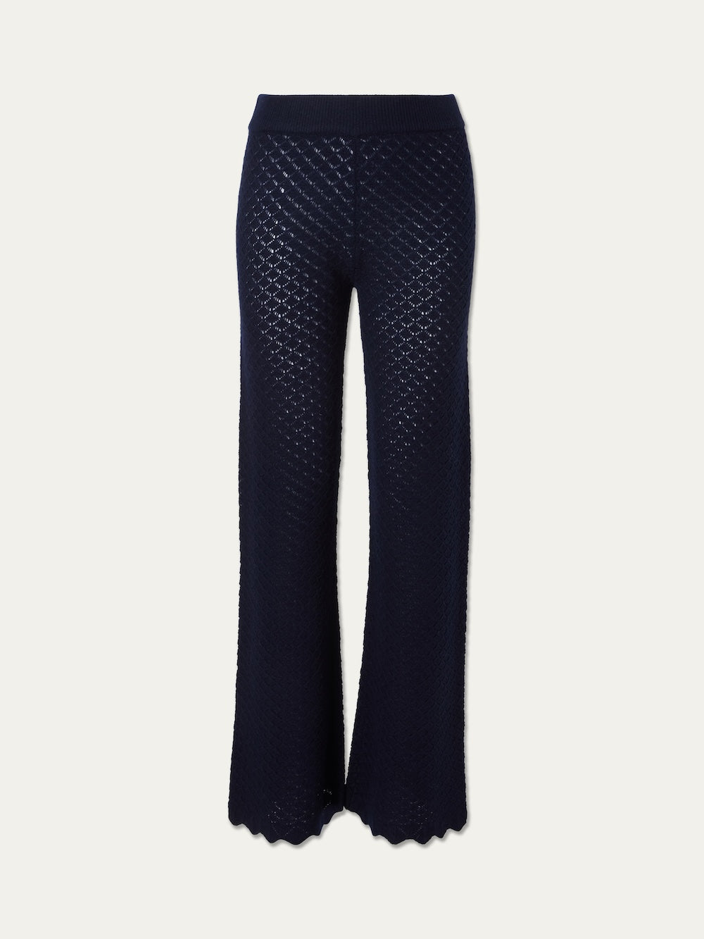 The Saeter Pant Women by We Norwegians is a navy blue, high-waisted pointelle knit pant featuring a wide-leg silhouette and scalloped hem, shown against a plain white background.