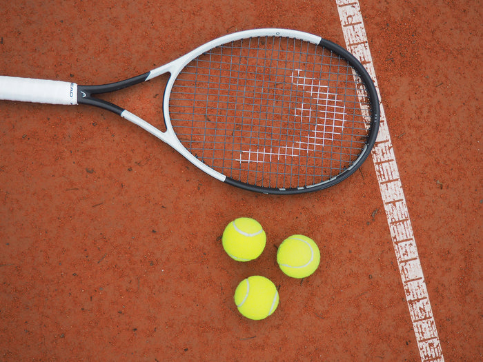 Tennis racket, with tennis balls on a tennis court