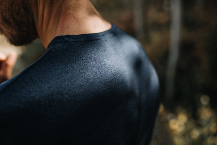 A man wearing a Merino Wool T-Shirt, the image zooms in to show the warp and weft of the fabric