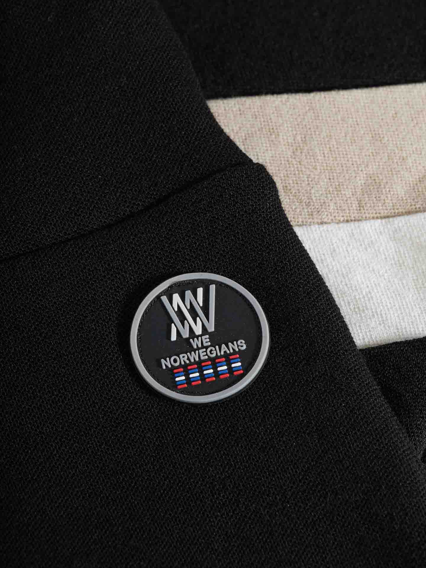 A small black circular pin with the text "WE NORWEGIANS" and several colored stripes, attached to a pair of Voss ColBlock Leggings Women's by We Norwegians.