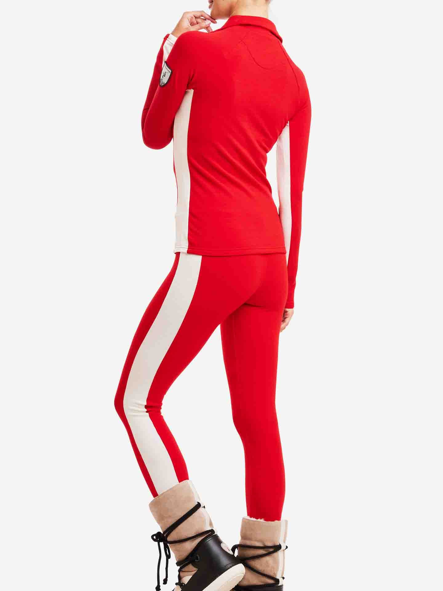 A person is wearing the Voss Leggings Women by We Norwegians, part of a red and white athletic outfit with a race stripe design that includes a long-sleeve top. They are showing their back to the camera and also sporting beige winter boots with black laces and fur lining.