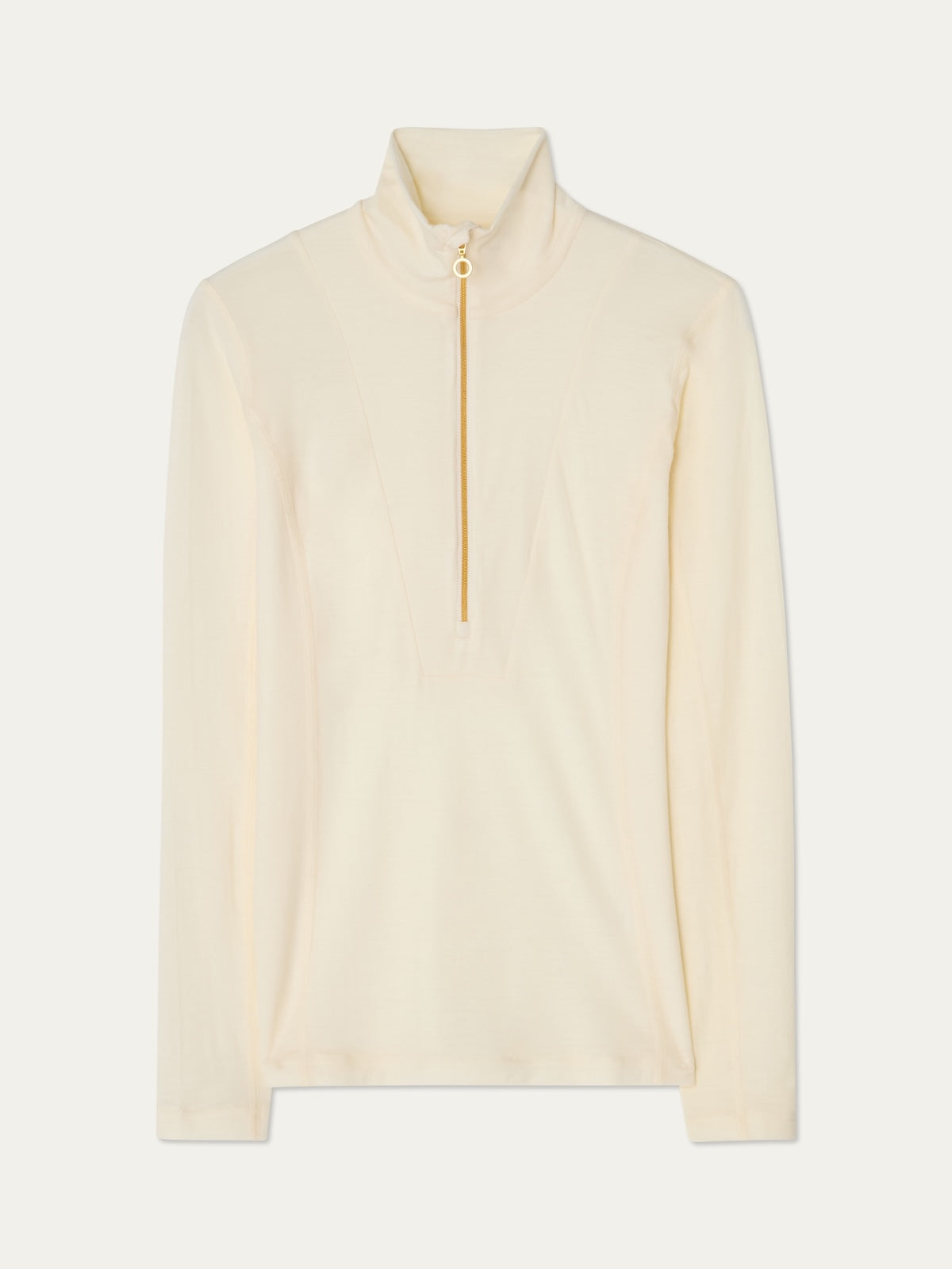 The We Norwegians Sno Merino Zip Up Women is a long-sleeved, cream-colored pullover top featuring a high collar and a central gold half-zip closure, crafted from breathable jersey fabric. This Scandinavian luxury base layer combines style and comfort for everyday wear.