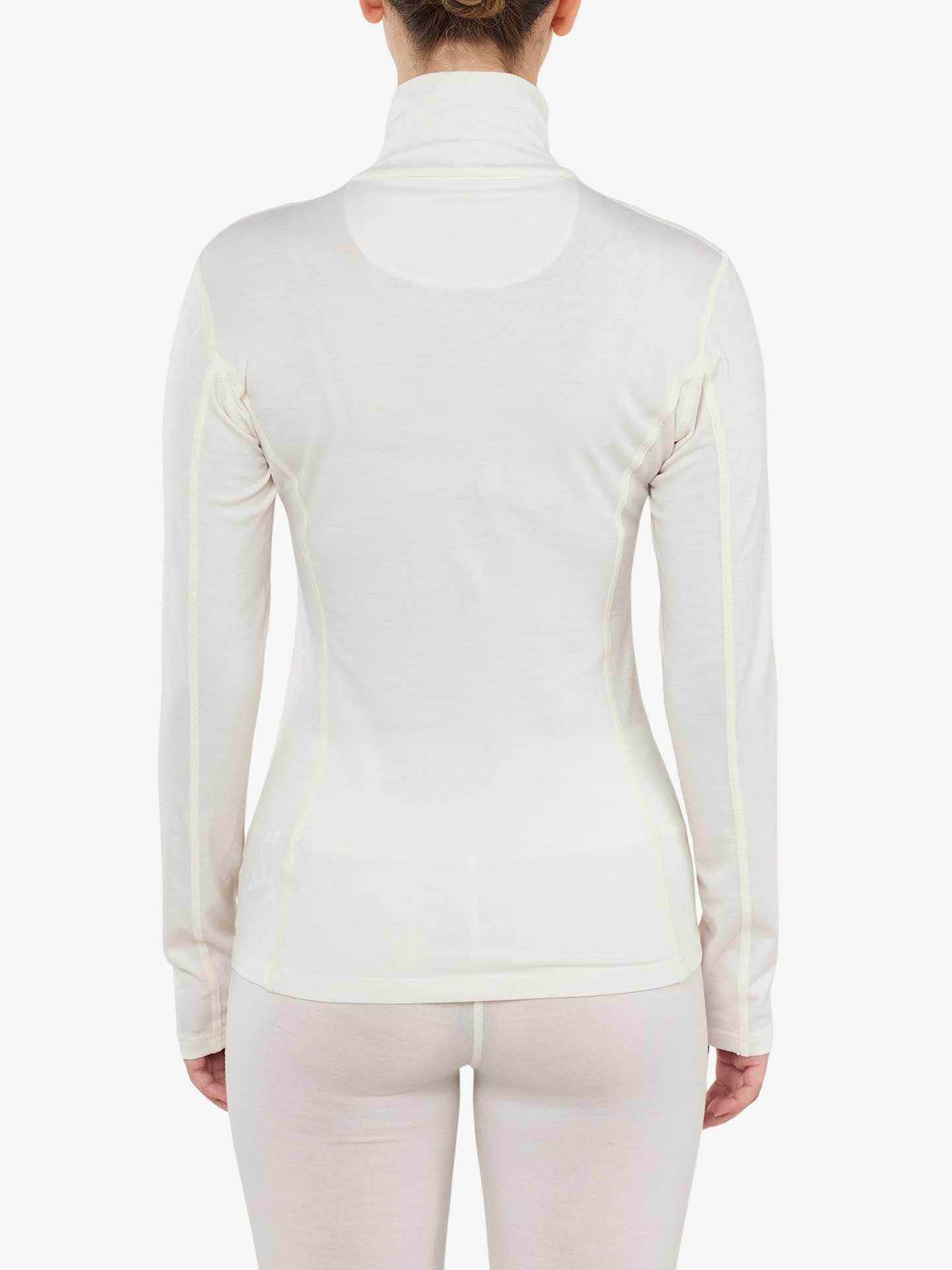 A woman wearing the Sno Merino Zip Up from We Norwegians is viewed from behind. The long-sleeve, light-colored thermal top made of super fine merino wool features a high collar and a slim fit. The image showcases her back, arms, and part of her legs against a plain white backdrop.