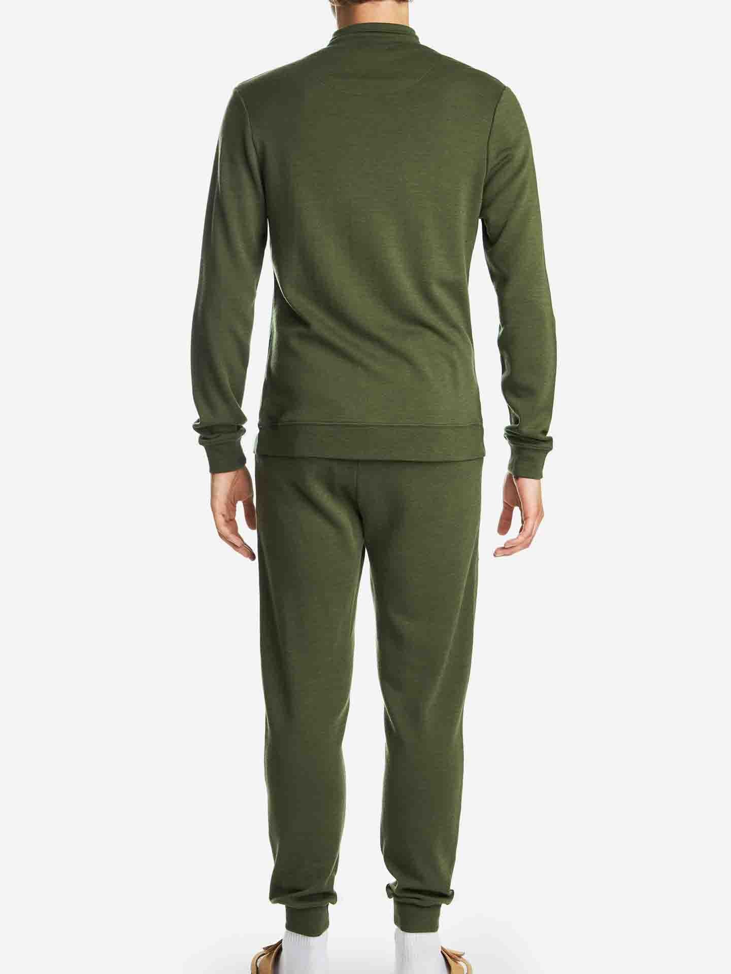 A person is shown from the back, wearing an olive green, long-sleeve tracksuit with matching Tind Joggers Men Olive Green by We Norwegians. The individual is also wearing white socks and brown shoes. The relaxed fit ensemble stands out against the plain white background.