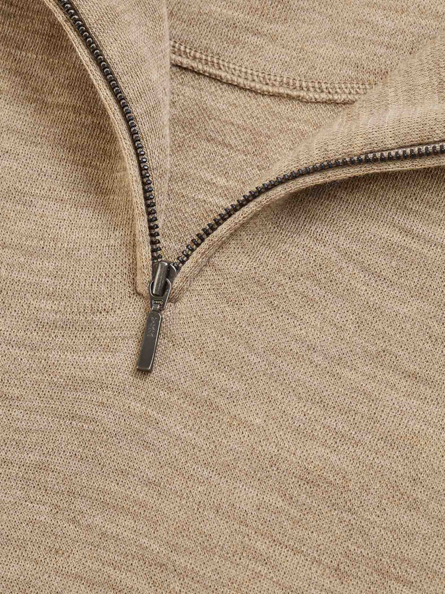 Close-up of a partially unzipped Tind 1/4 Zip Sweater Men Camel from We Norwegians, featuring a metal zipper. The jacquard knit garment appears to be crafted from soft Merino wool, showcasing fine details and craftsmanship in its heathered texture.