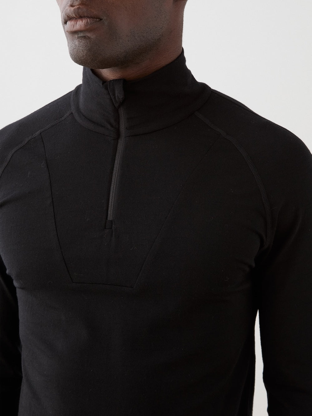 We Norwegians | FW25 | Mens Sno Zip-up_Black | A close fit, breathable base layer with a stand collar, 1/4th zipper opening and long sleeves on an off-white background | Close-up